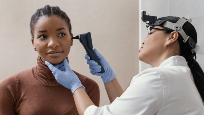 Médica fazendo exame numa paciente observando seu ouvido