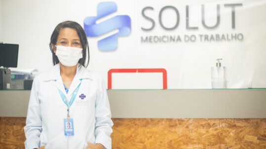 Colaboradora da Solut em frente a logo da clínica