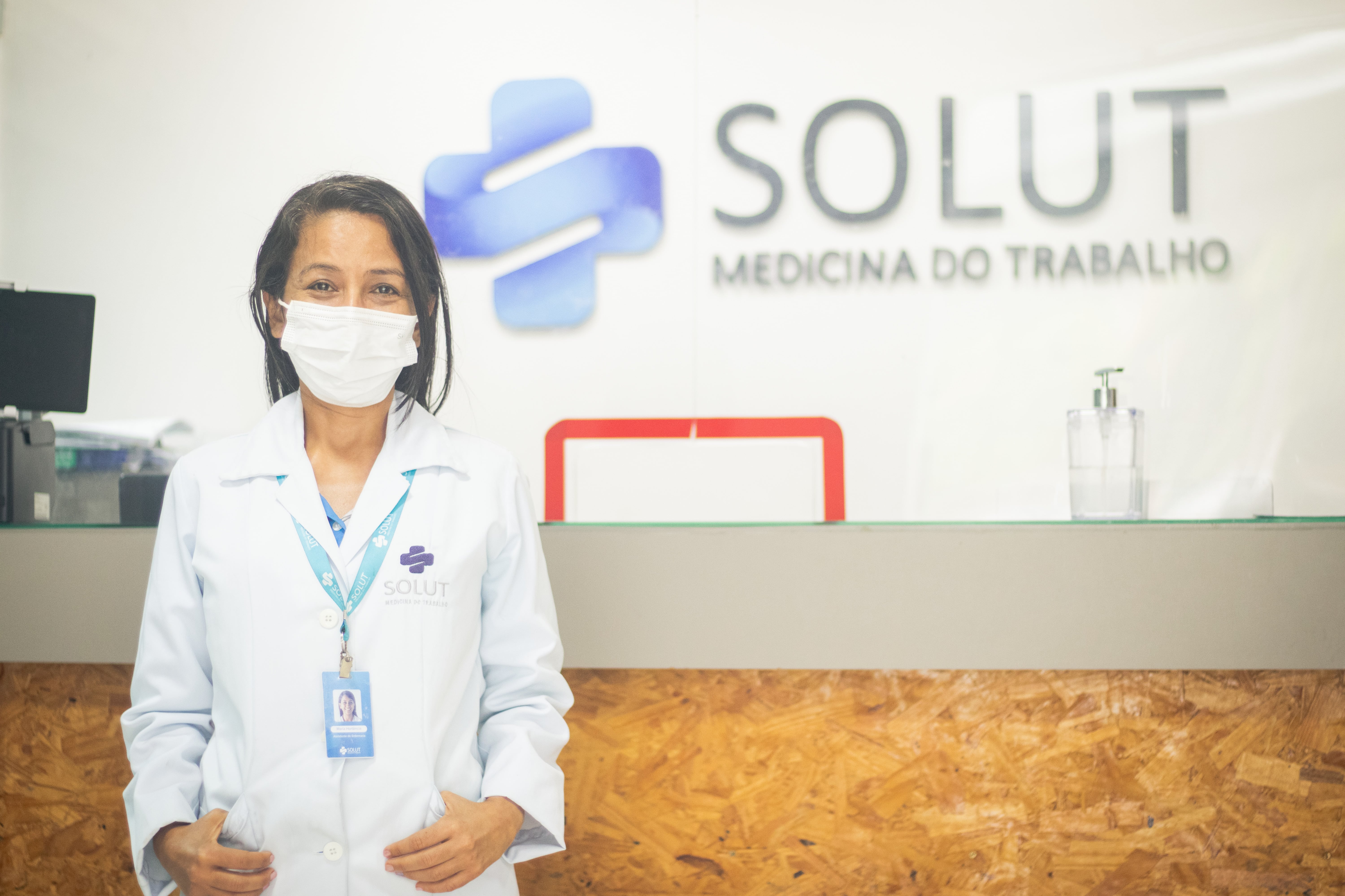 Colaboradora da Solut em frente a logo da clínica